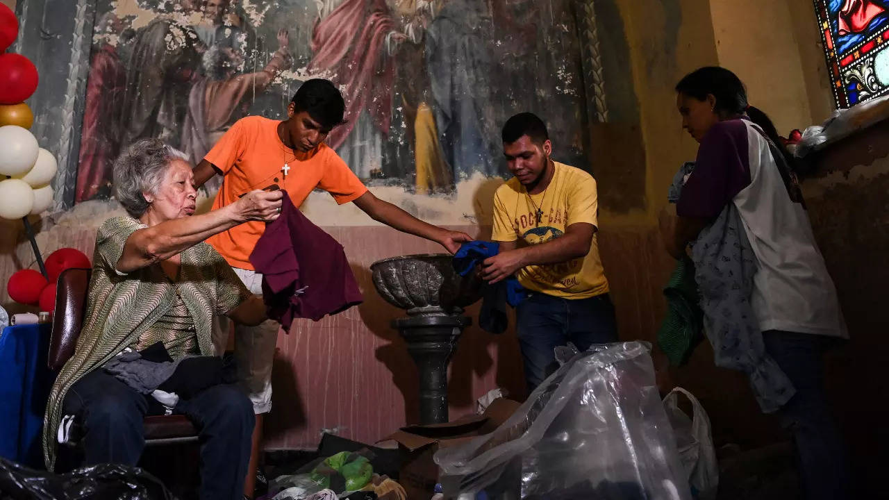 Volunteers sort donated clothing for victims of a landslide during heavy rains in Las Tejerias, Aragua state, Venezuela, on October 10, 2022 (AFP) 