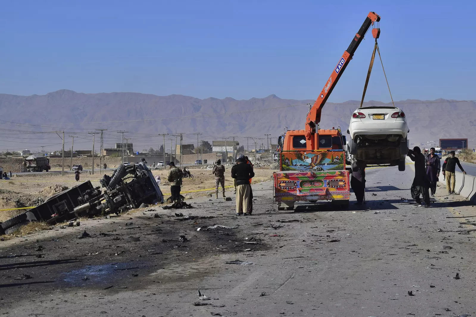 Workers remove a damage car while security officials inspect the site of a suicide bombing in Quetta, Pakistan, Wednesda. (AP)