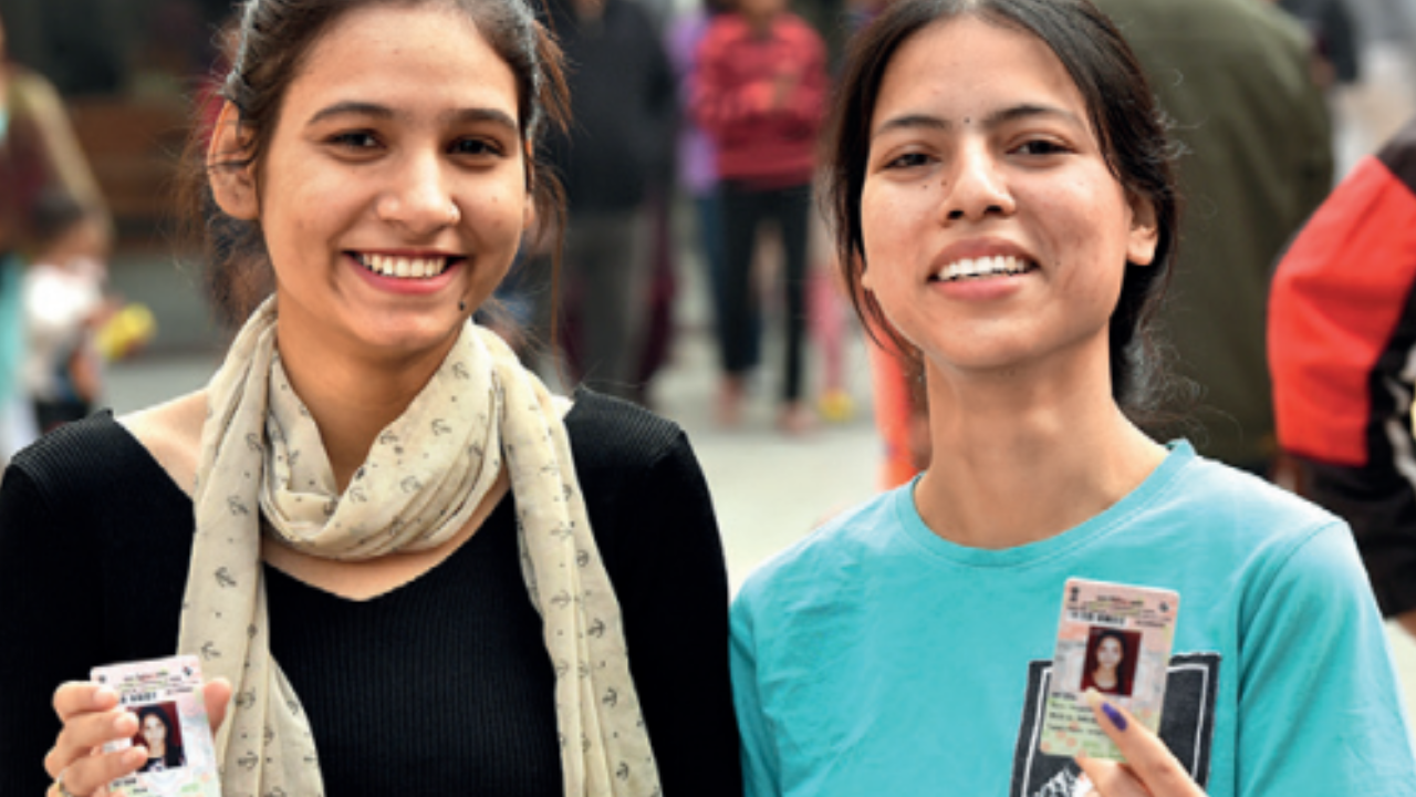 First-time voters flash their ID cards after casting their votes in east Delhi on Sunday
