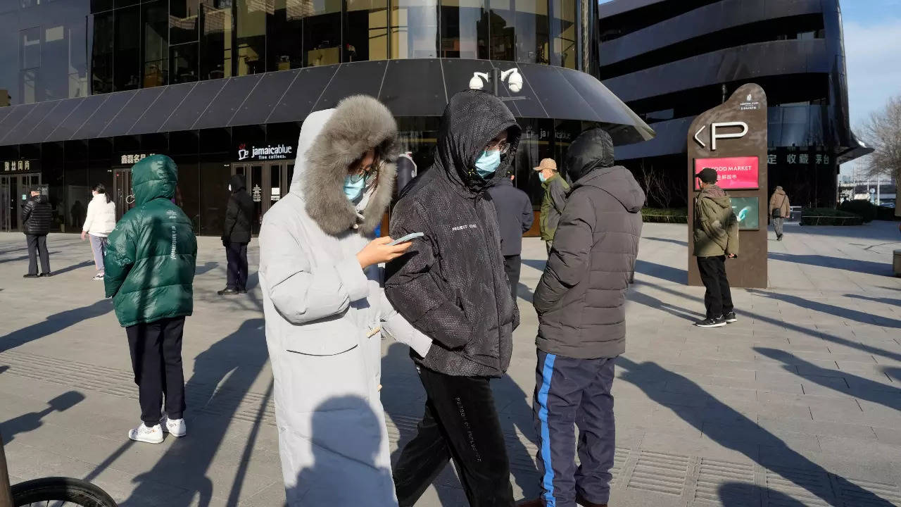 Residents wearing masks walk past others in line for COVID tests in Beijing, Wednesday, Dec. 7, 2022. (AP) 