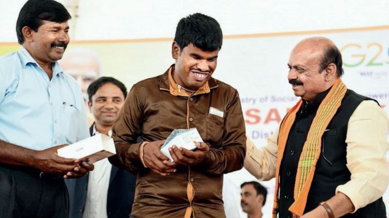 CM Basavaraj Bommai interacts with a beneficiary during an event to distribute devices to specially abled people in Nanjangud on Sunday