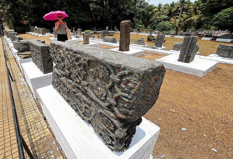 A foreign tourist walks past stone exhibits at an open heritage museum in Old Goa on Tuesday, the World Heritage Day