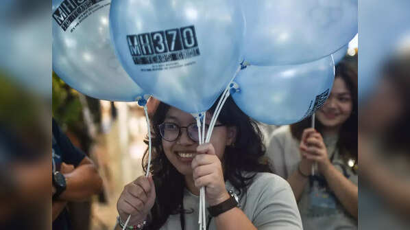 People hold balloons to mark 10 years of plane disappearance