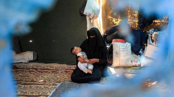 Woman holds child inside the camp