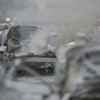 Charred vehicles smolder as emergency crews respond to urban blaze