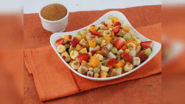 A bowl of fruit with black salt and lemon