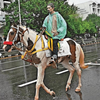 Cyclone Ditwah Live: A handler in a rain poncho rides his horse along Kamarajar Salai near the Marina Beach