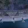 Ajith standing on top of a dam surrounded by gun toting men