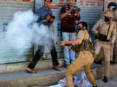 A police officer fires tear gas shell towards stone-pelters