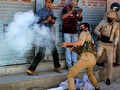 A police officer fires tear gas shell towards stone-pelters