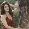 Ravishing in a red gown, posing beside a tree
