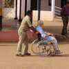 A policeman taking a senior citizen to polling booth on wheel chair