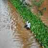 People rest along a divider of a road flooded at Wadala after heavy rains in Mumbai.