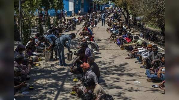 Migrant workers, daily wagers, laborers and homeless people wait for food outside a government-run shelter.