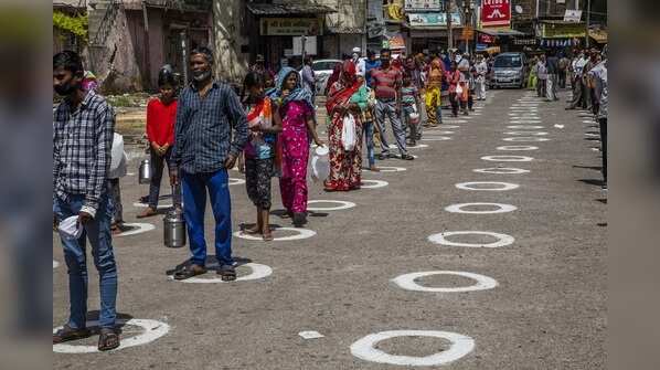 Migrant workers stand in circles to receive free food in New Delhi on March 31.
