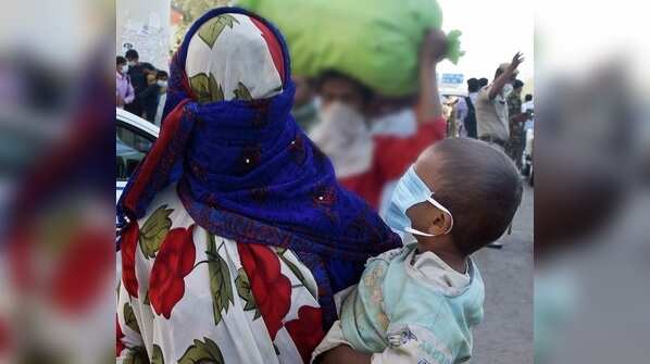 A migrant worker with her child waits for a bus to return to their village at Anand Vihar in Delhi