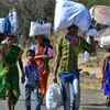 Migrant workers carry their belongings as they walk along a road to return to their villages on April 01, 2020.