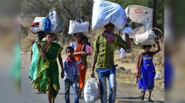 Migrant workers carry their belongings as they walk along a road to return to their villages on April 01, 2020.