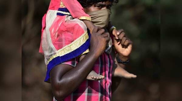 Migrant workers carry their belongings as they walk along a road to return to their villages on April 01, 2020.