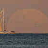 A yacht sails past as the moon rises in Sydney (AP Photo)