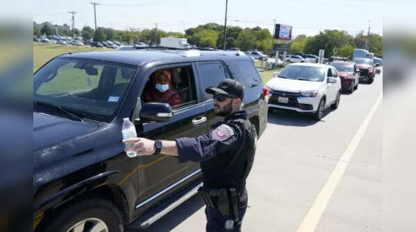 A Burleson, Texas, SWAT officer directs traffic to a parking area for families arriving to be reunited with their children, Wednesday.
