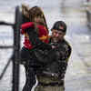 ​A volunteer carries a young girl to high ground