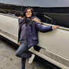 Sayli poses against a limousine