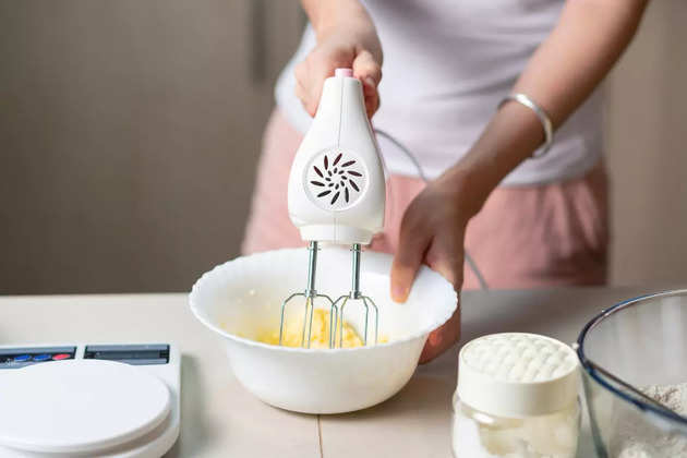 woman-using-electric-mixer-to-mix-ingredients-for-dough-while-making-picture-id1266827047
