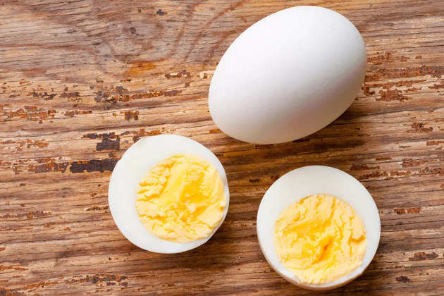 boiled-egg-cutout-and-raw-egg-with-shell-on-wooden-background-picture-id961697202