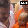 A child dresses up as UP chief minister Yogi Adityanath and carries a toy bulldozer, as she arrives at the BJP office in Lucknow along with her father