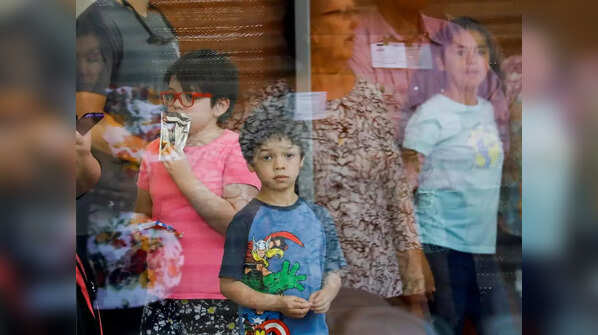 A child looks on through a glass window from inside the Ssgt Willie de Leon Civic Center, where students had been transported from Robb Elementary School after a shooting, in Uvalde, Texas.
