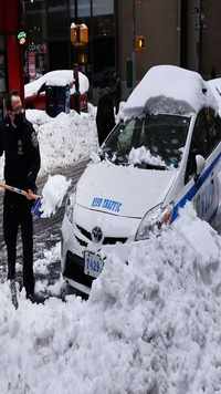 A police officer clears snow from his car in Manhattan in New York City.