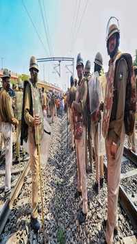 Security personnel stand guard as <i class="tbold">bhartiya kisan union</i> activists block a railway track