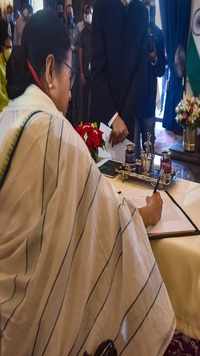 Mamata Banerjee signs a register during the swearing-in-ceremony to take the oath as the chief minister.