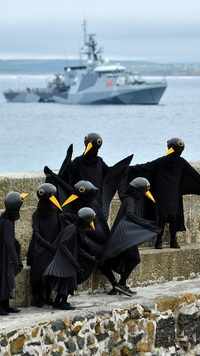 As leaders arrived, climate change activists dressed up as black birds and gathered at St. Ives
