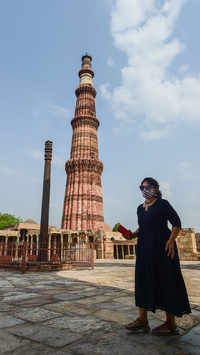 A visitor stands near Qutub Minar adhering to Covid norms