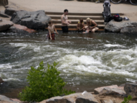 People cool off in the water at the confluence of the South Platte River and Cherry Creek in Denver