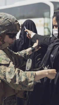 A <i class="tbold">us marine</i> checks a woman at Hamid Karzai International Airport, Kabul.