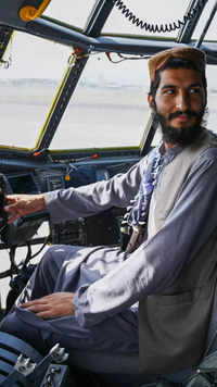 A Taliban fighter sits in the cockpit of an <i class="tbold">afghan air force</i> aircraft at the Kabul airport.