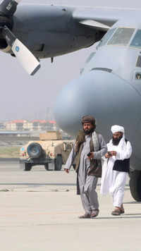 Taliban walk in front of a military airplane after the US troops withdrawal from Afghanistan.