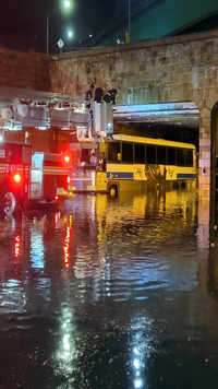 A <i class="tbold">fire department</i> crew attempts to rescue passengers on a bus stuck in flood waters in New York.