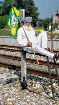 A farmer holds the flag of Bhartya Kisan Union as he sits between railway tracks in Patiala.