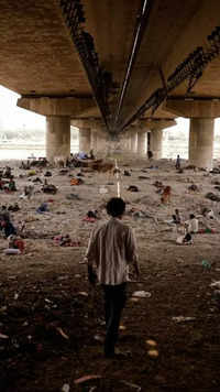 People sleep on the Yamuna river bed under a bridge on a hot summer day in New Delhi, India