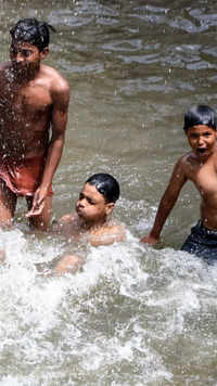 Children taking bath in a water pond to cool themselves on a hot day in Delhi.