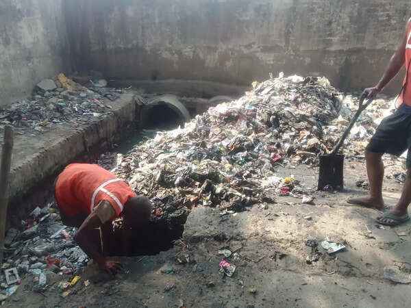 Sanitation workers clean drains without safety gear