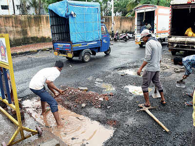 Workers fill potholes with debris, bricks