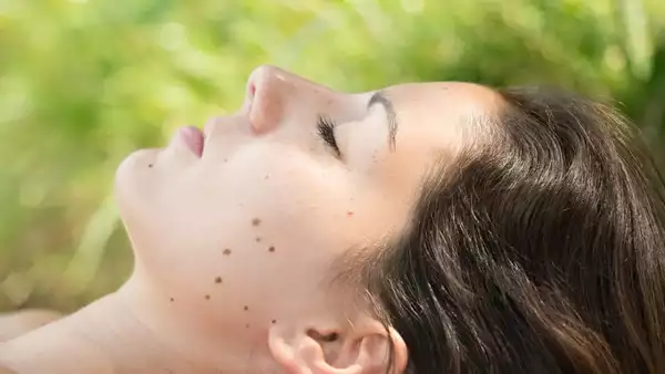 looking at viewer, sitting, legs crossed, mole under mouth, moles