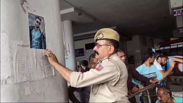 Police official puts up a poster of missing terrorist Yasir Bhat