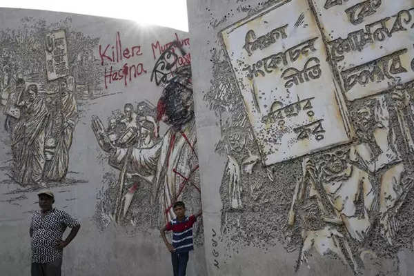 People stand near vandalised murals of Sheikh Mujibur Rahman, father of Sheikh Hasina who resigned as Prime Minister on Monday, in Dhaka, Bangladesh, Aug 6, 2024.