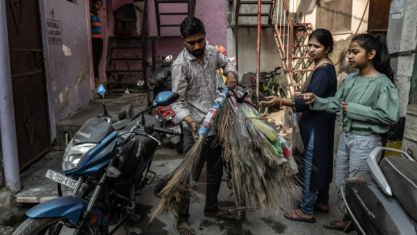 A man selling brooms and dusters to residents of Khadda Colony, where ash dust has inundated the neighborhood.